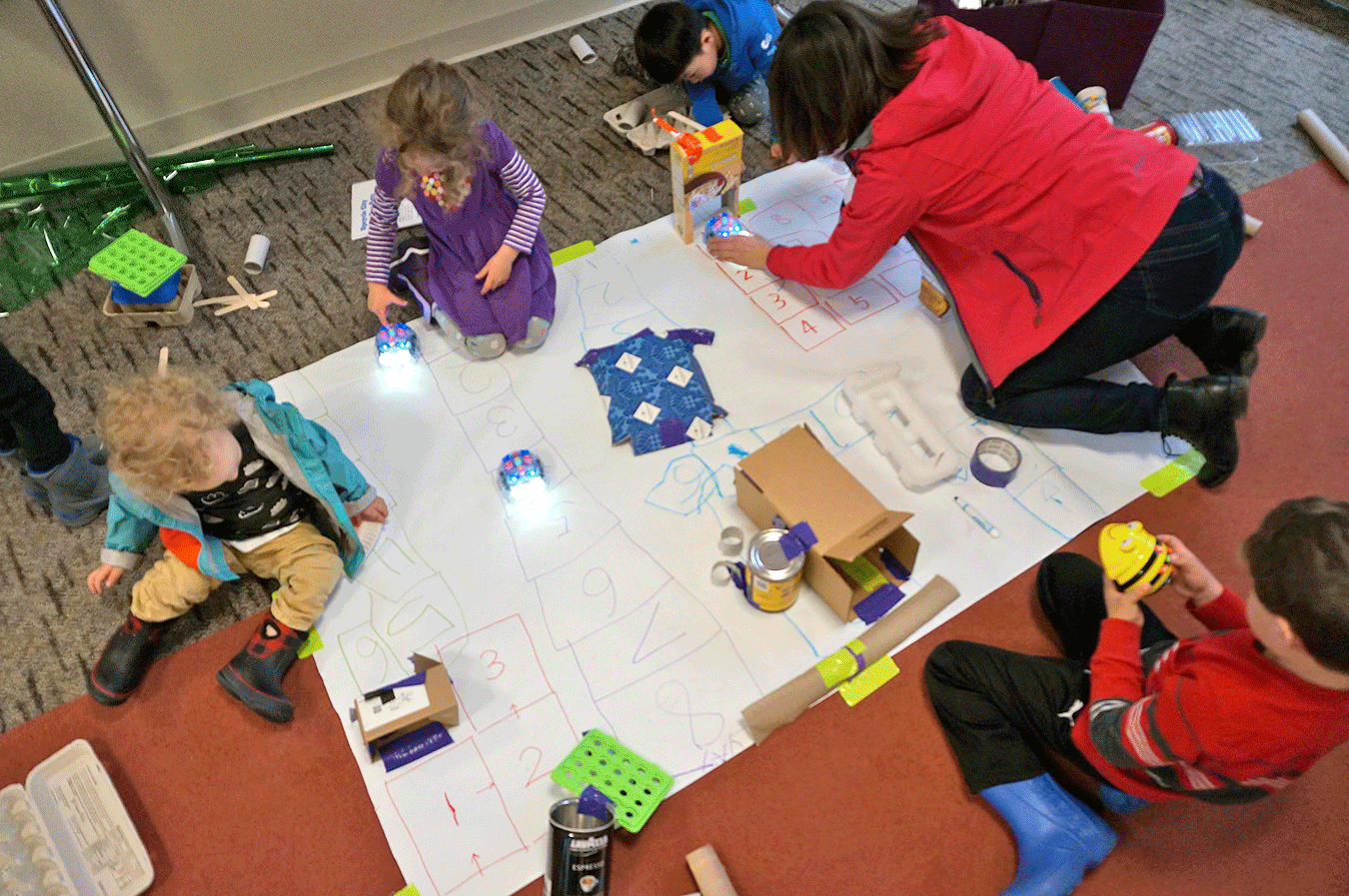 Families with young children engage in making cities with Bee-Bot robots.
