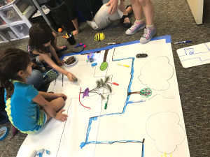 Wonderlab students engaged in making: using BeeBots, recyclables, and natural materials to design their own forrest pathways