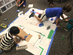 Wonderlab students engaged in making: using BeeBots, recyclables, and natural materials to design their own forrest pathways