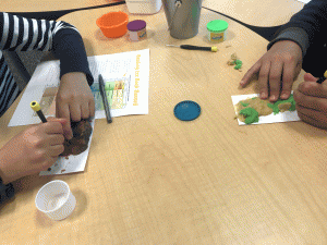 6th grade students are creating a base layer of playdough to model their fossil record. They are flattening playdough down onto an index card and using screw drivers to mold their rock formation.